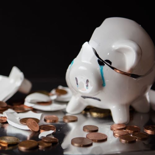 Ein weinendes Sparschwein, zerbrochen mit Kleingeld